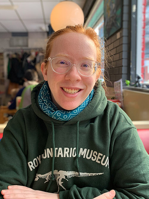 Victoria Tolson woman in a green hoodie with a bandana and glasses