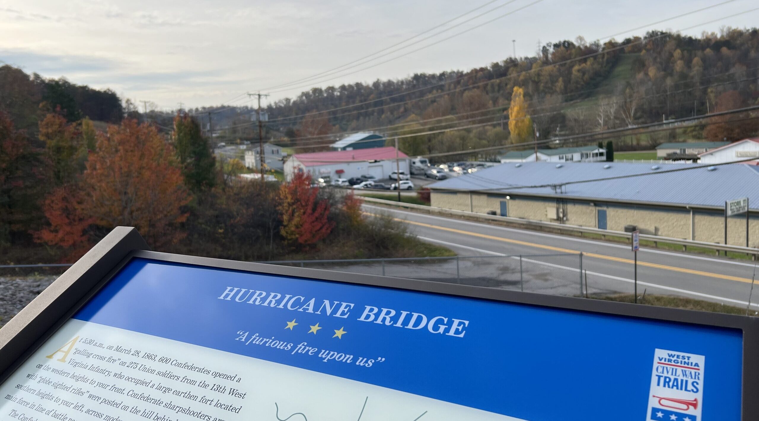A civil war trails road sign in front of a wheat field.