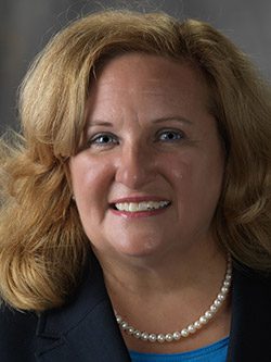 headshot of woman with blond hair wearing pearls