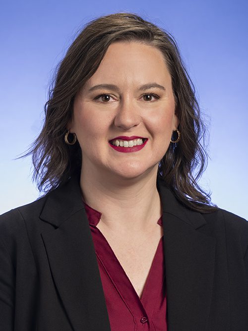 headshot of woman with burgandy shirt and dark jacket